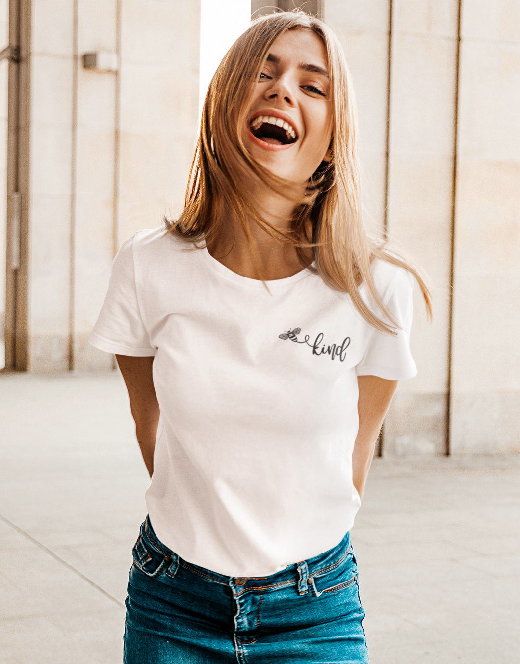 Woman wearing white t-shirt with a picture of a bumble bee and the word kind.