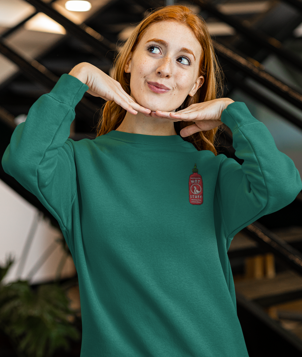 Red haired model wearing a green hot sauce sriracha sweatshirt